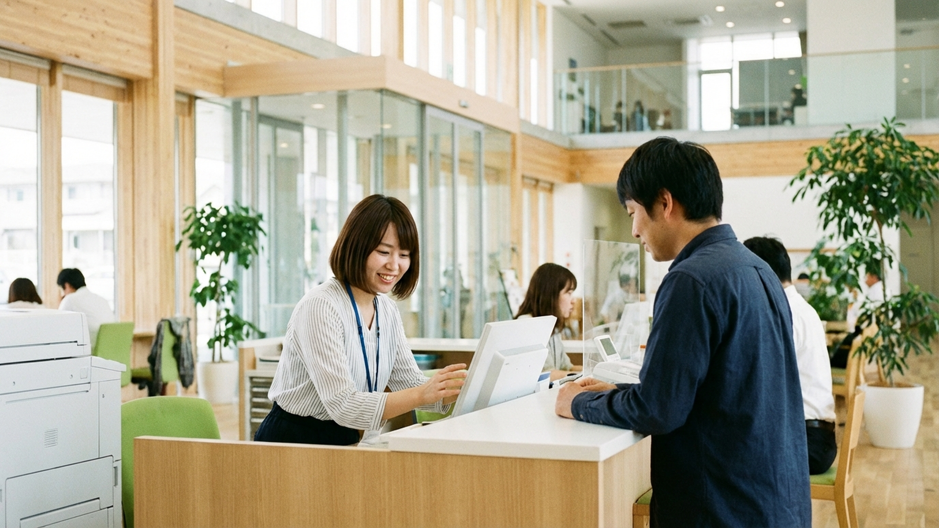 日本の地方自治体の庁舎窓口で可愛い日本人女性職員がパソコンで住民対応をしている様子